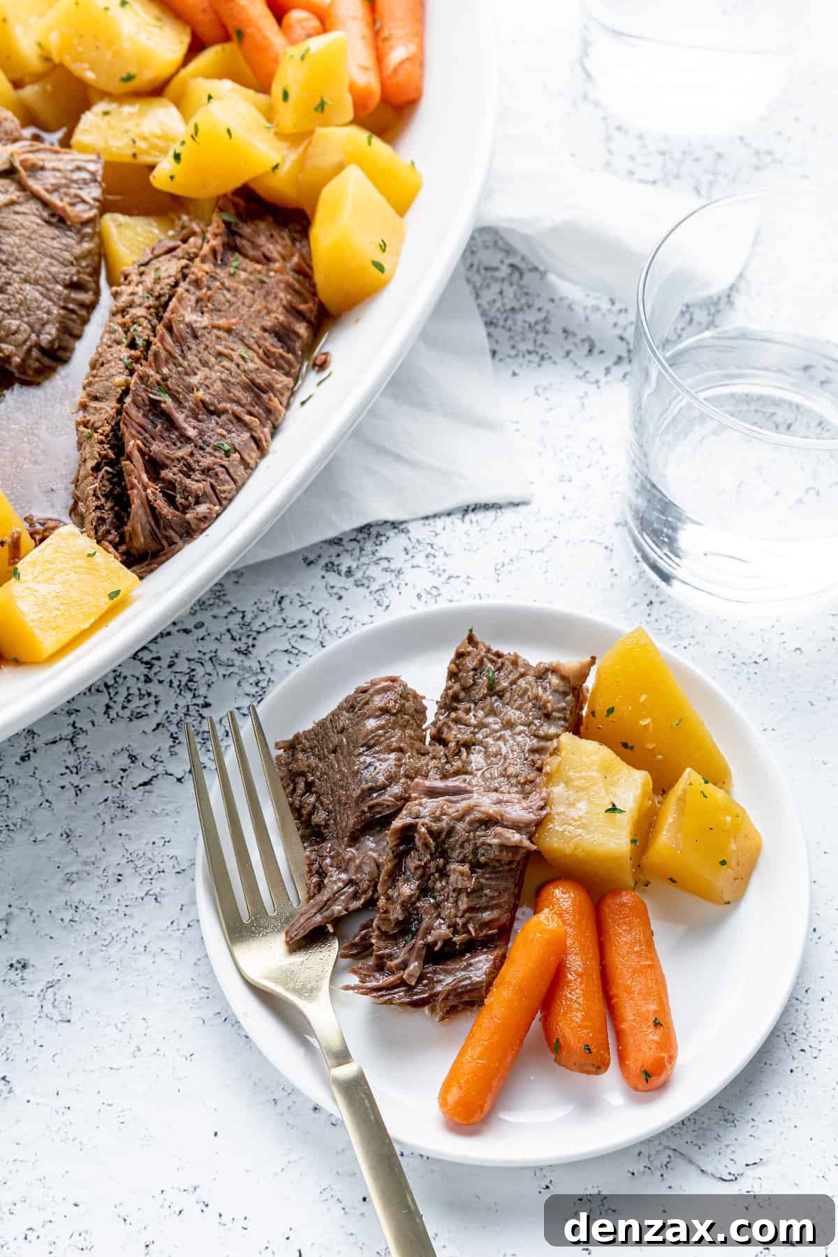 A white plate with pot roast, carrots and potatoes