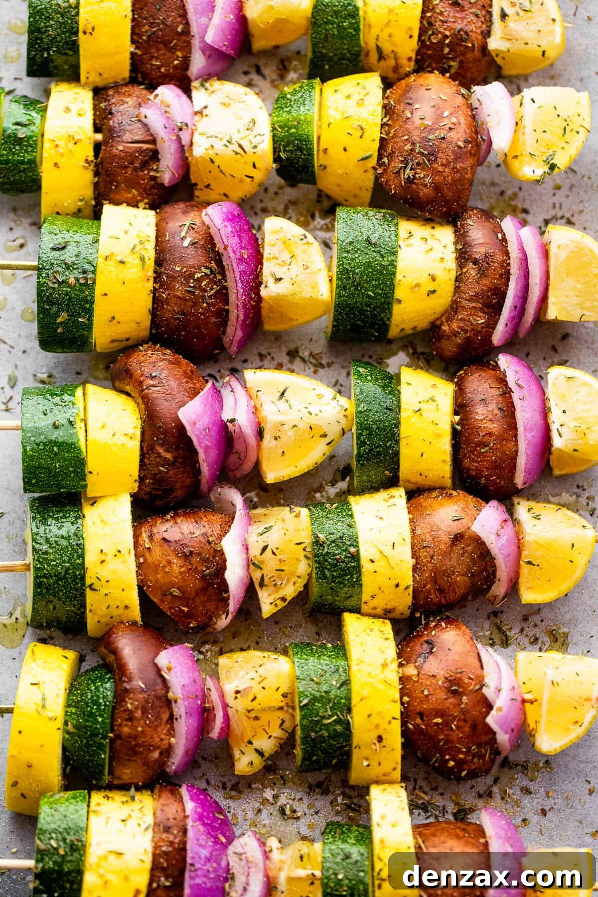 eight squash, red onions, lemons, and mushrooms threaded on wooden skewers