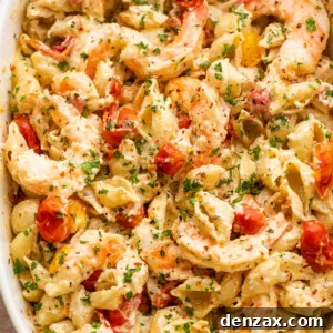 white baking dish with shrimp and pasta tossed with a cream cheese sauce and cherry tomatoes