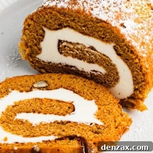Pumpkin cake roll with one slice cut out and the filling exposed.