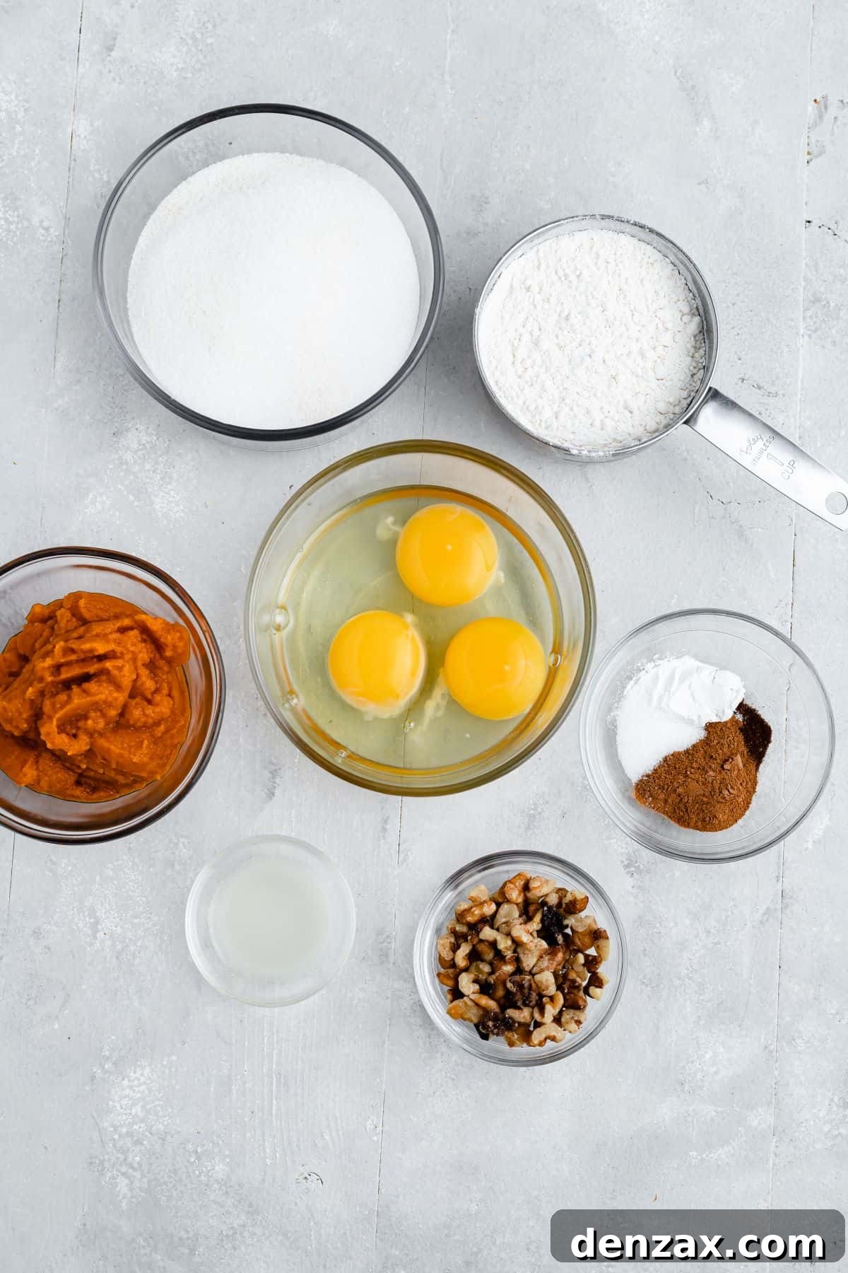 Clockwise from top: flour, spices, walnuts, lemon juice, pumpkin puree, sugar. Center: 3 eggs.