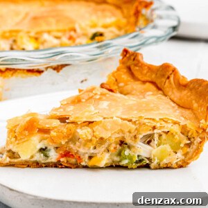 In the background, the baked chicken pot pie. In the foreground, a slice of the pie on a plate with a fork.