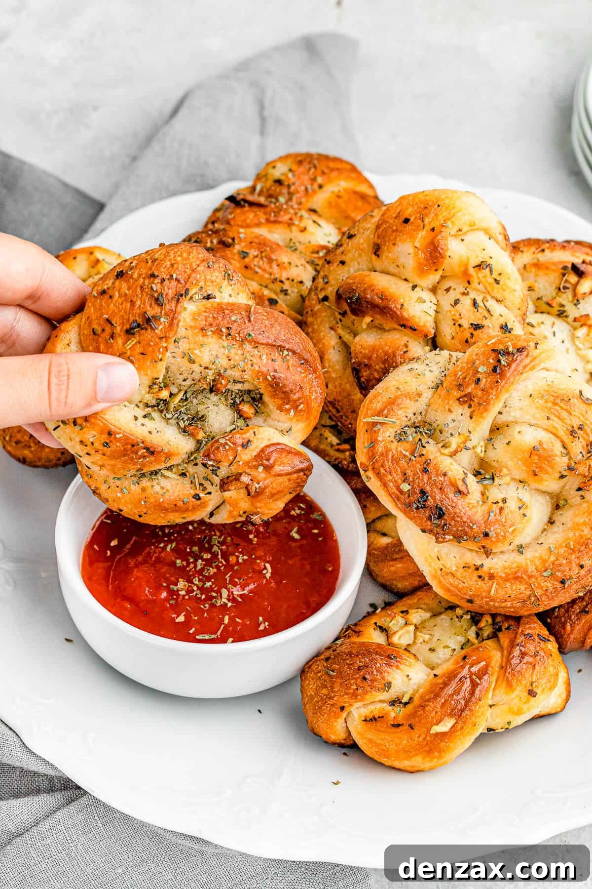 Easy Homemade Garlic Knots Recipe — Soft, Buttery & Ready in 30 Minutes 7 dipping garlic knots in marinara sauce.