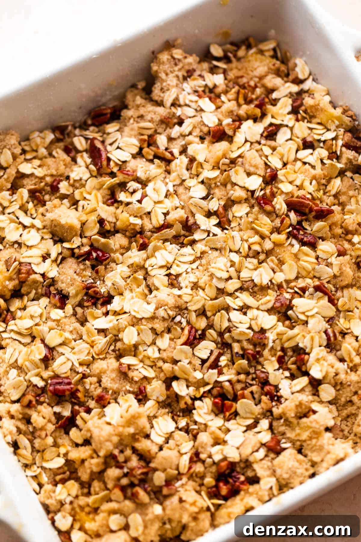 Perfect Peach Crisp Recipe: Easy Summer Dessert with Oats 5 squared baking dish with peach slices covered in oats, flour, and pecans