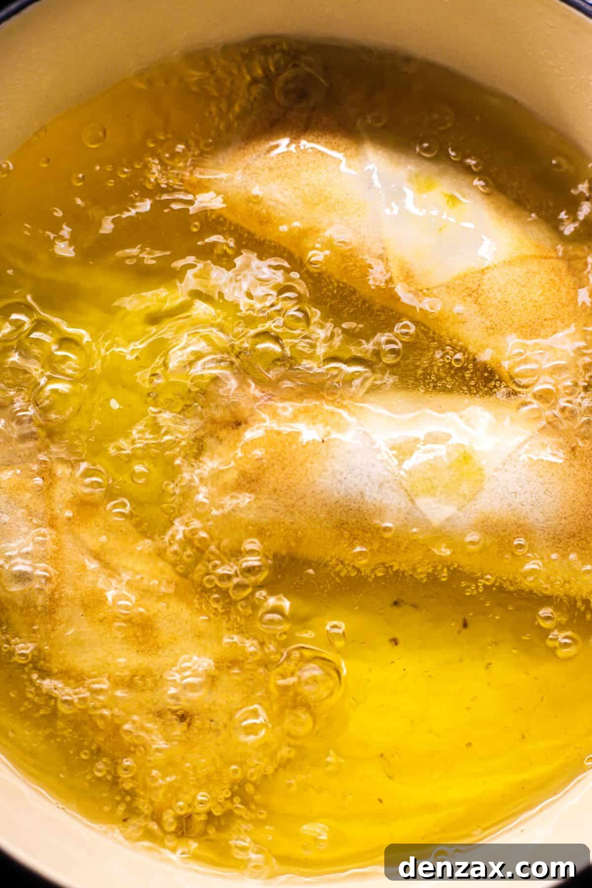 Crispy Golden Vegetable Spring Rolls Recipe 7 Spring rolls being deep fried in a skillet.