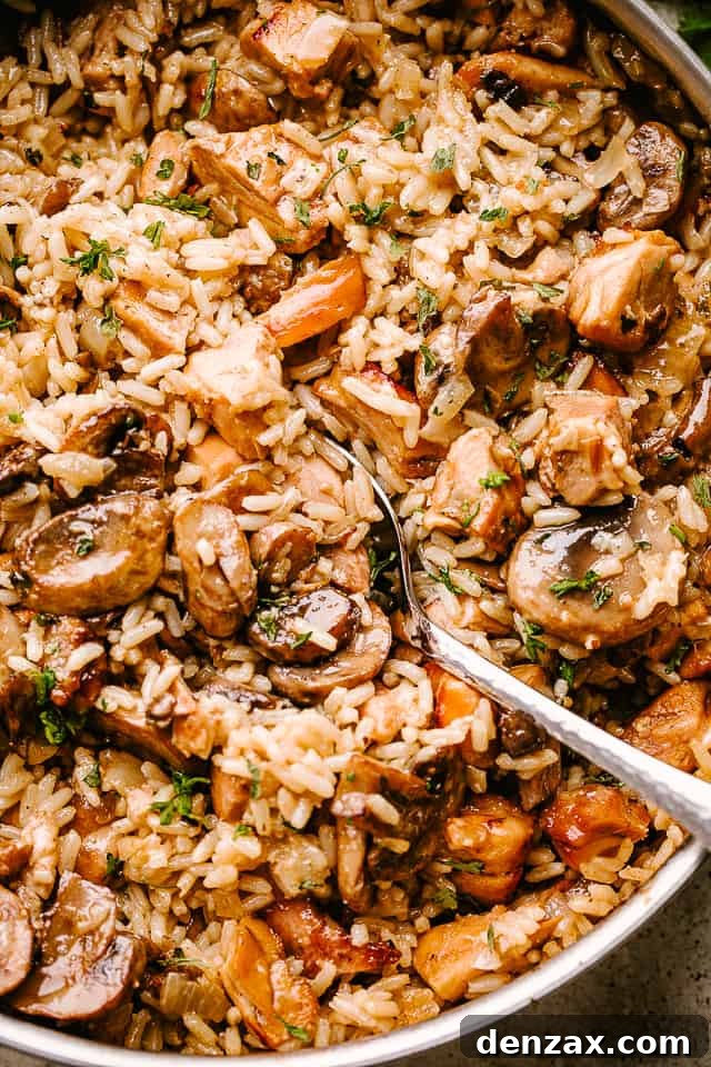 Chicken and mushrooms sauteing in a pan with rice