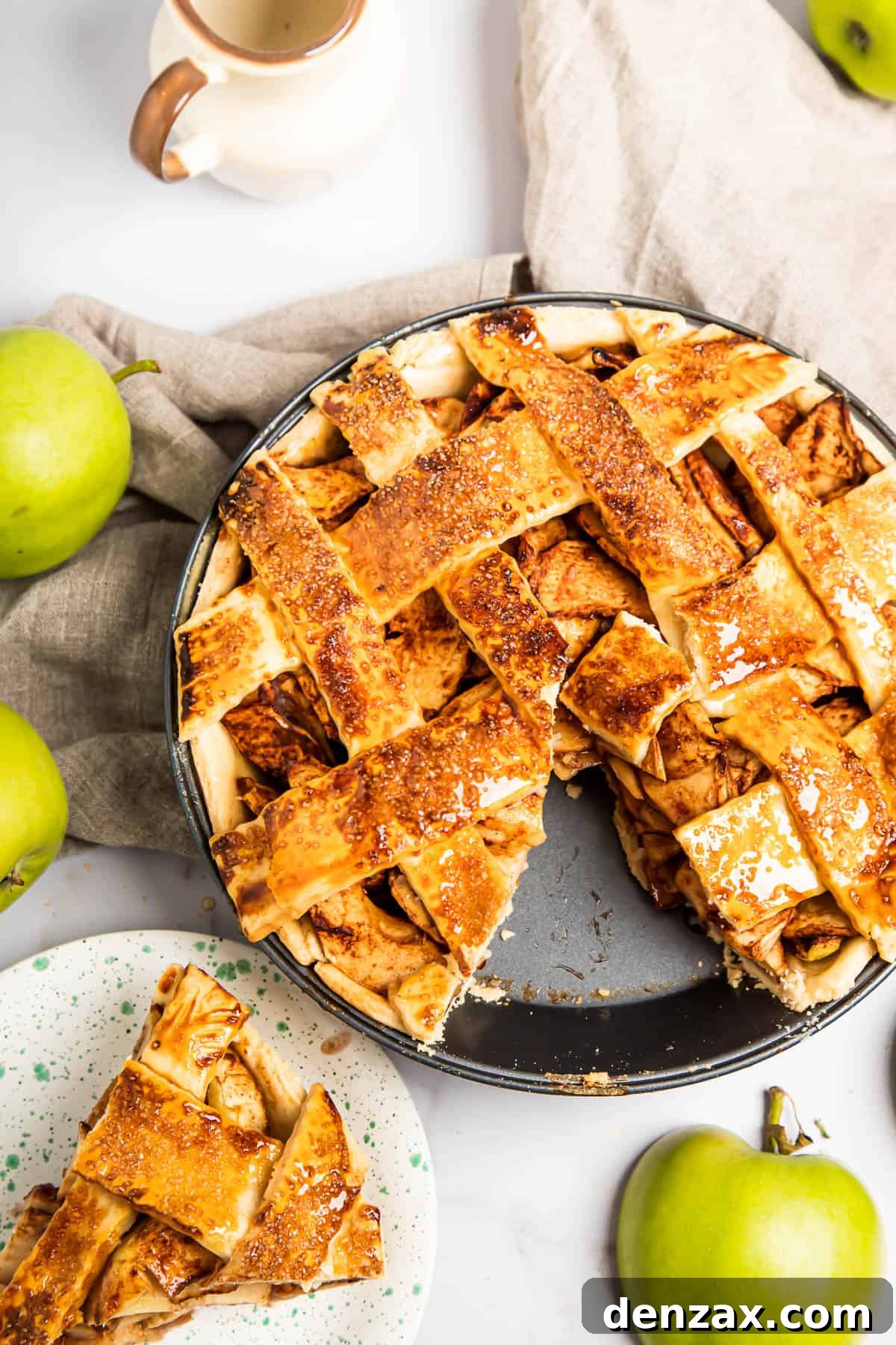 An apple pie with a slice cut out of it. The slice is on a saucer nearby.
