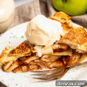 a slice of apple pie topped with ice cream on a plate with a fork