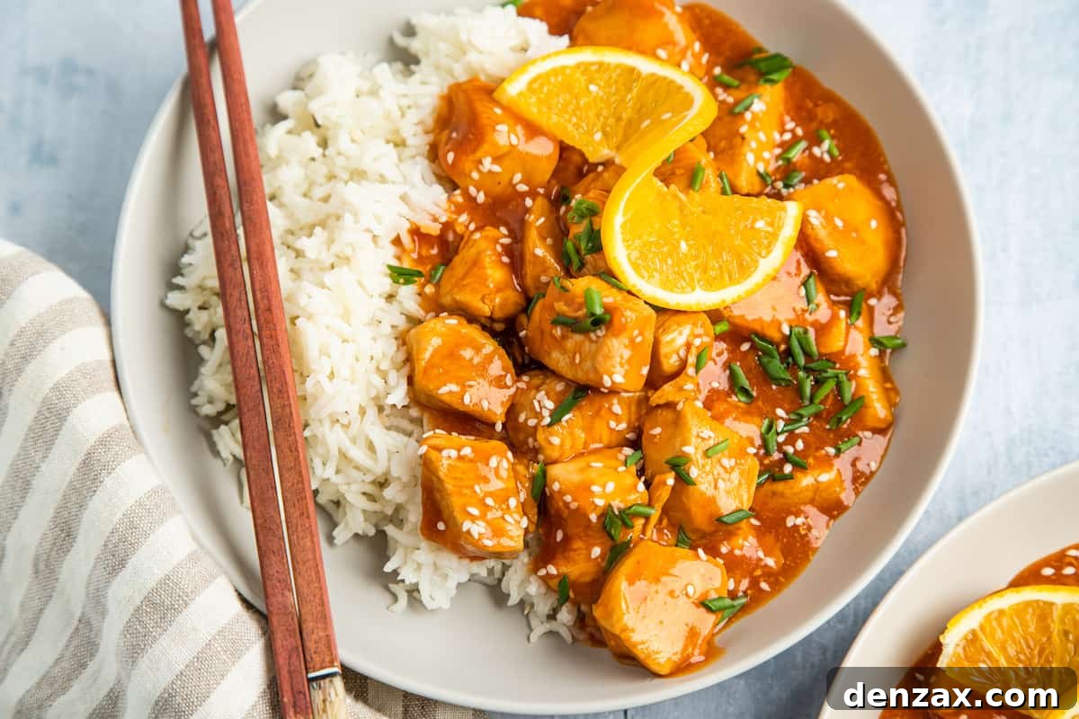 Instant Pot Orange Chicken Recipe: Sticky, Tangy Weeknight Meal 8 A serving of orange chicken, garnished with orange wedges, on a plate with white rice and chopsticks.