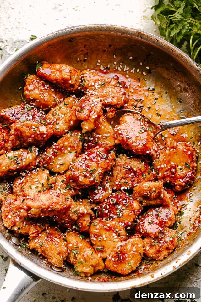 Crispy Honey Sesame Chicken being stirred in a pan