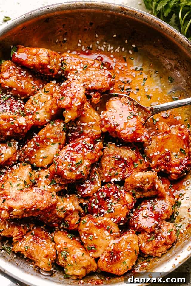 Crispy Honey Sesame Chicken being stirred in a pan
