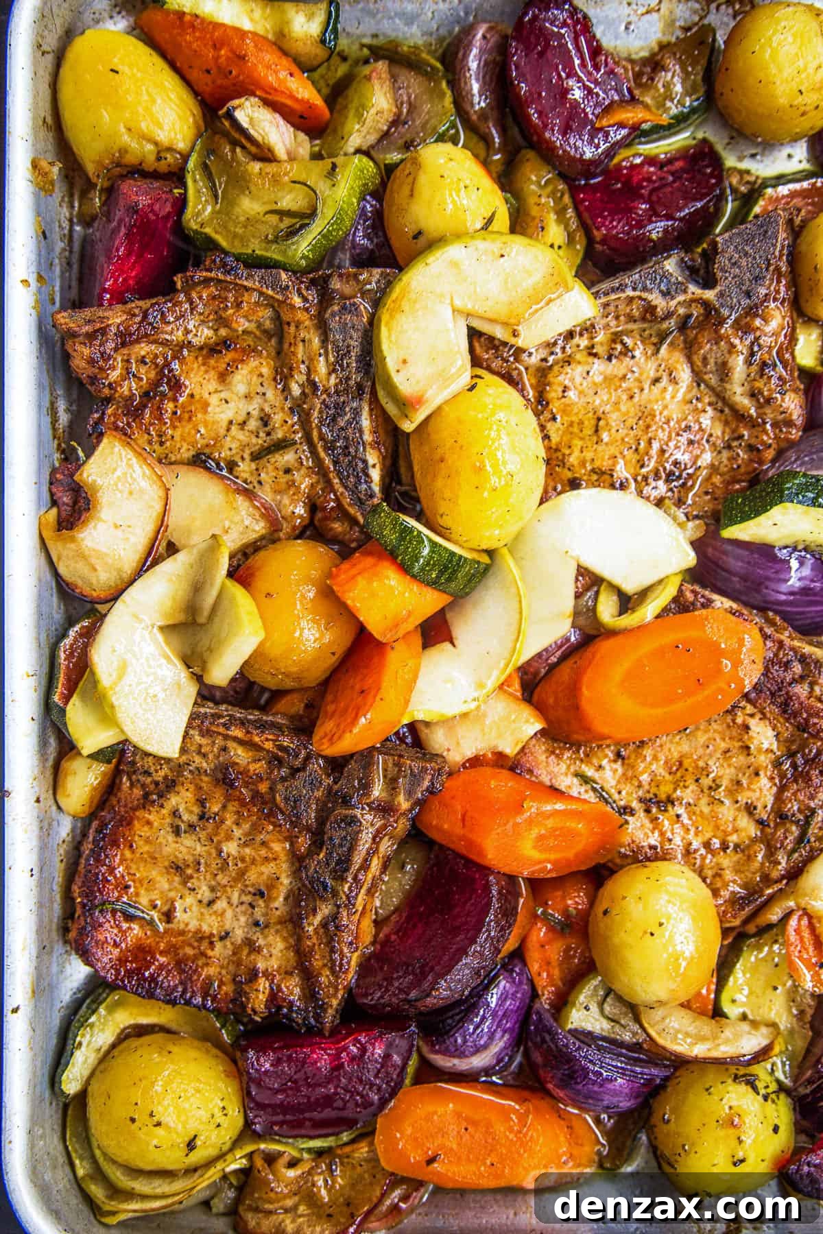 Roasted Pork Chops with Apples and Winter Vegetables 6 A close-up overhead shot of the baking dish with pork chops, apples, and vegetables cooked with apple juice and rosemary.