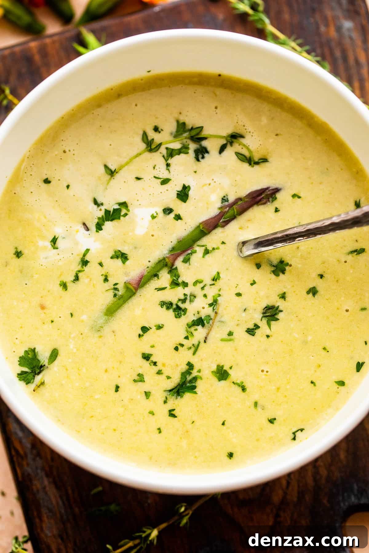 Cream of Asparagus Soup in a white bowl with a spoon inside.