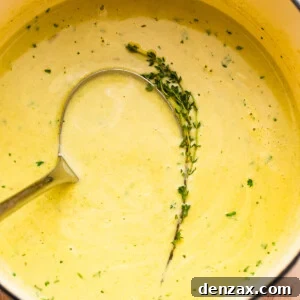 cream of asparagus soup in a pot with a ladle inside it.