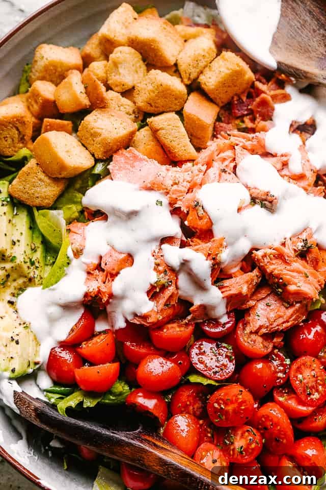 Salmon BLT salad plated and topped with dressing
