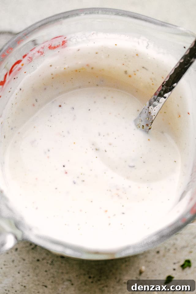 A mayonaise based dressing for Salmon BLT salad in a mixing cup with a spoon