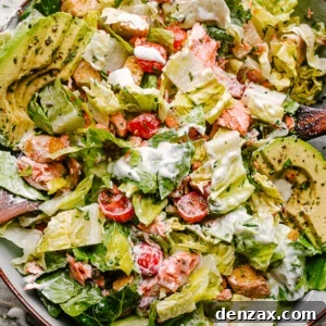 Salmon BLT salad plated with dressing mixed throughout