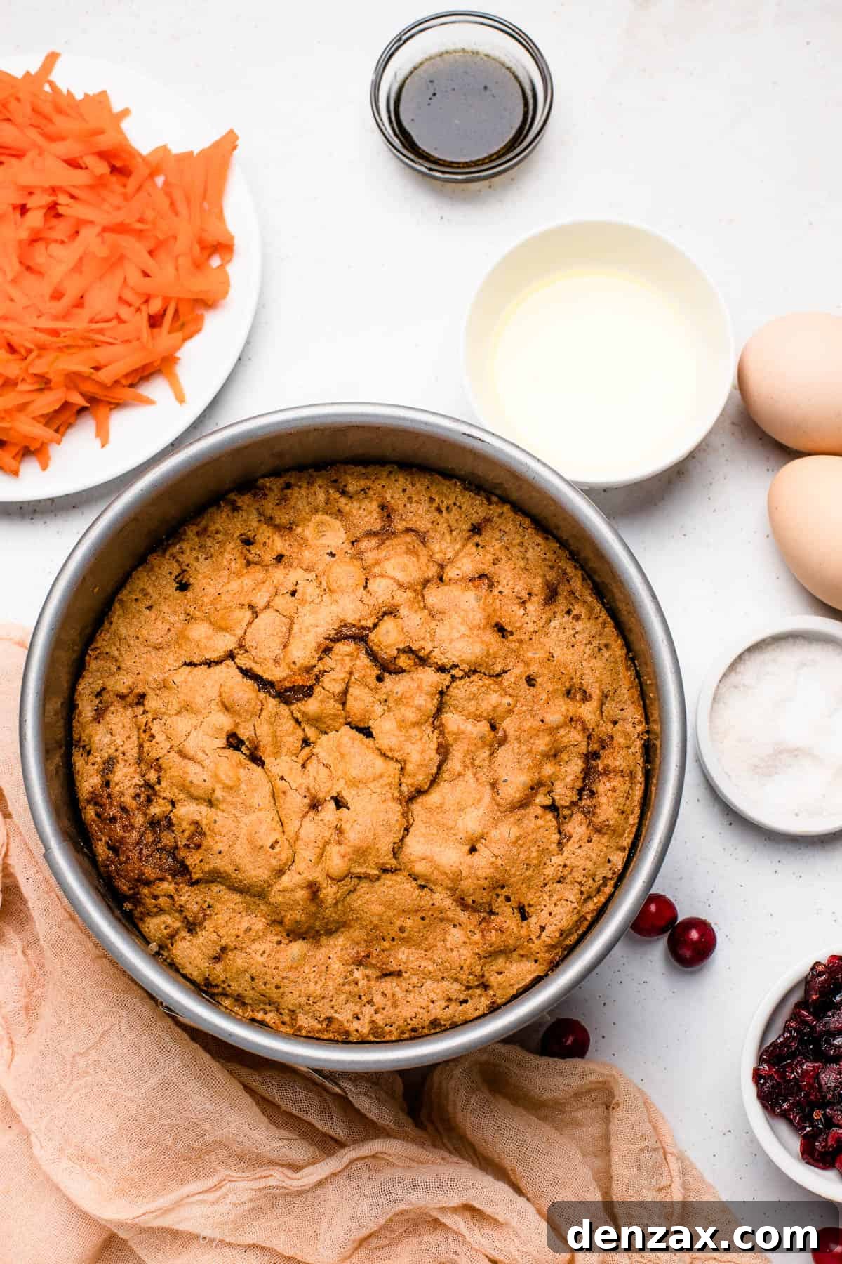 Carrot Cake with Sugared Cranberries: Moist Spring Dessert 5 A baked cranberry carrot cake in the baking pan, cooling on a countertop with several small dishes of ingredients nearby.