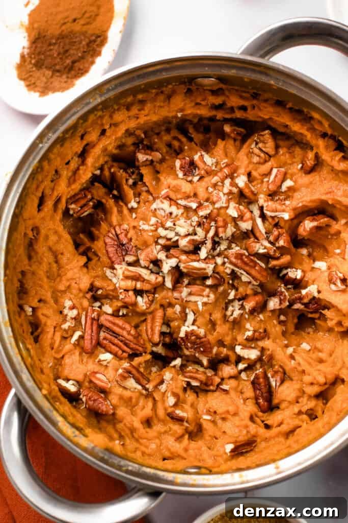 A pot with mashed sweet potatoes topped with chopped pecans.