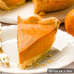A pumpkin pie slice on a white plate with a fork.