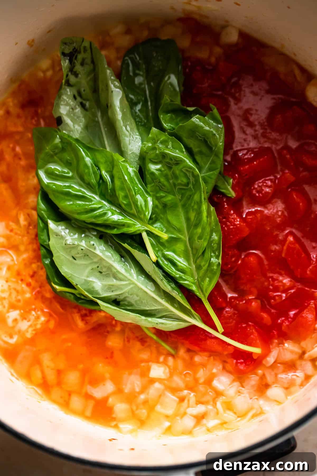 sauteeing canned tomatoes, onions, and basil leaves.
