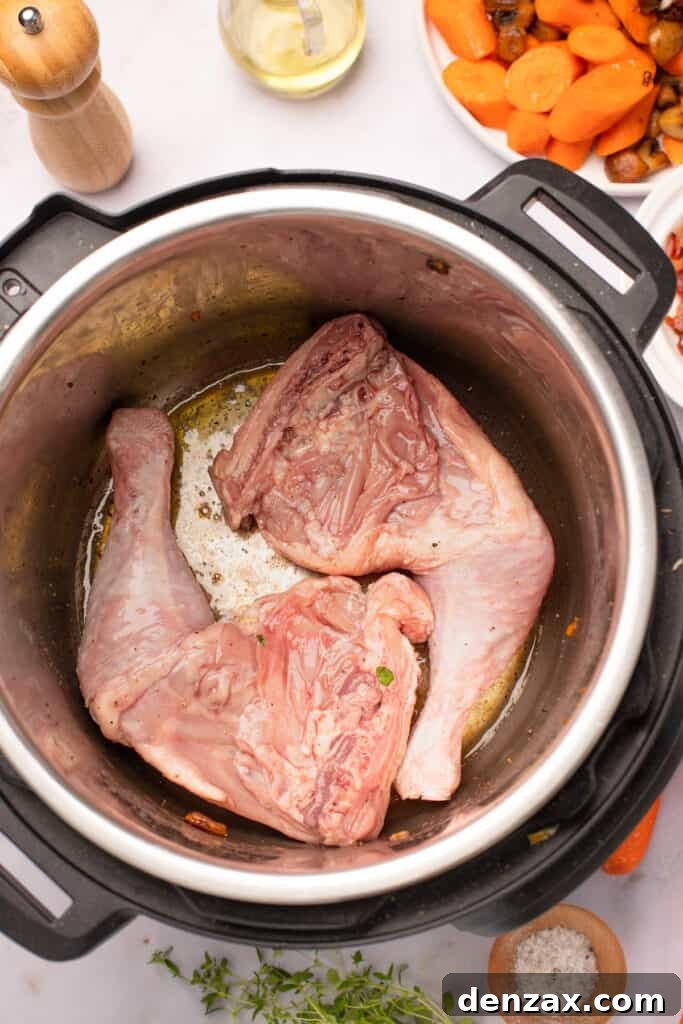 Marinated chicken legs frying in the bottom of an Instant Pot.